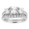 A silver engagement ring features three large round diamonds and a band adorned with smaller diamonds.
