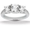 A three-stone engagement ring with a central round diamond flanked by two smaller round diamonds on a silver band.