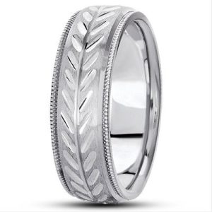A silver wedding band features a leaf pattern carved around its surface.