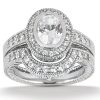 A silver engagement ring with an oval center stone surrounded by smaller sparkling diamonds.
