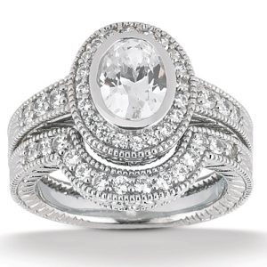A silver engagement ring with an oval center stone surrounded by smaller sparkling diamonds.