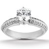 A silver ring with a large round diamond at the center and smaller diamonds set along the band.