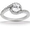 A silver engagement ring features a large round diamond centerpiece surrounded by smaller diamonds along the band.