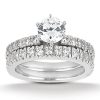 A silver wedding ring set featuring a central round diamond surrounded by smaller diamonds on both bands.
