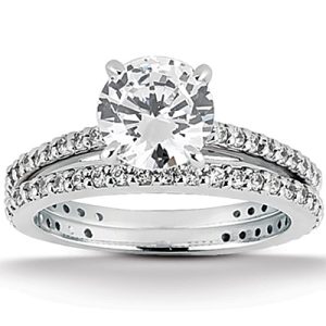 A silver engagement ring featuring a large round diamond center stone flanked by smaller diamonds on the band.