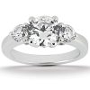 A three-stone engagement ring featuring a large central round diamond flanked by two smaller round diamonds on a polished band.