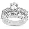 A silver ring features a central round diamond surrounded by smaller diamonds arranged in a floral pattern.