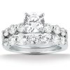 A silver ring set features a central round diamond surrounded by smaller diamonds on a curved band.