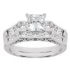 A silver engagement ring features a large square diamond centerpiece surrounded by smaller round diamonds.