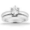 A silver-colored engagement ring with a round diamond setting sits atop a matching wedding band.