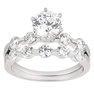A silver engagement ring features a large round diamond at the center, flanked by smaller round diamonds in a tiered design.