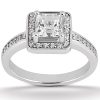 A silver engagement ring features a square-cut center stone surrounded by smaller round diamonds.