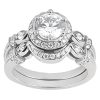 A silver engagement ring features a large round diamond surrounded by smaller stones in an ornate setting.