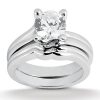 A silver engagement ring set features a large round diamond at the center with two interwoven bands.