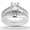 A silver engagement ring features a central round diamond surrounded by smaller diamonds along the band.
