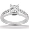 A silver engagement ring features a central princess-cut diamond surrounded by smaller diamonds along the band.