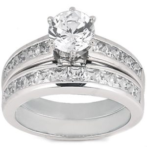 A silver ring set featuring a large round diamond center stone with smaller diamonds on either side.