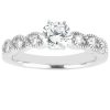 A silver engagement ring features a central round diamond with smaller accent diamonds along the band.