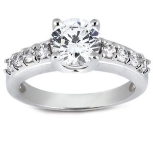 A silver engagement ring features a large central diamond surrounded by smaller diamonds along the band.