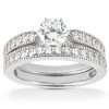 A diamond engagement ring set features a central round diamond surrounded by smaller pavé-set diamonds on a white gold band.