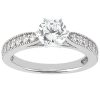 A silver engagement ring features a prominent round diamond center stone and smaller diamonds embedded along the band.