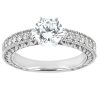 A silver engagement ring features a round brilliant cut diamond at its center, surrounded by smaller diamonds along the band.