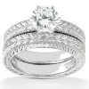 A silver engagement ring set featuring a prominent round diamond on top of an intricately designed band.