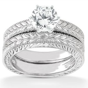 A silver engagement ring set featuring a prominent round diamond on top of an intricately designed band.