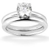 A silver engagement ring set features a large round diamond on top of a smooth band with another band below.