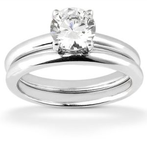 A silver engagement ring set features a large round diamond on top of a smooth band with another band below.