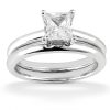 A silver wedding ring set featuring a solitaire princess-cut diamond on the top ring and a plain band below.