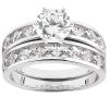 A silver wedding ring set features a large round diamond center stone surrounded by smaller diamonds along the band.