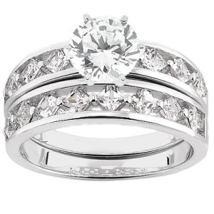 A silver wedding ring set features a large round diamond center stone surrounded by smaller diamonds along the band.