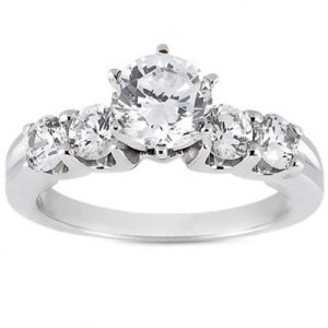 A silver ring with a central round-cut diamond and three smaller diamonds on each side.