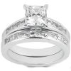 A silver engagement ring features a large square-cut center stone surrounded by smaller rectangular stones.