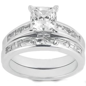 A silver engagement ring features a large square-cut center stone surrounded by smaller rectangular stones.