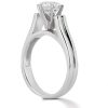 A silver engagement ring with a prominent diamond sits on a smooth surface.