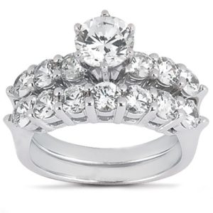 A silver ring features a central round diamond surrounded by smaller diamonds in a tiered arrangement.