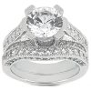 A silver engagement ring features a large round diamond centerpiece surrounded by smaller diamond accents.