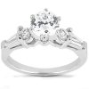 A silver engagement ring features a large central round diamond flanked by two smaller diamonds on each side.