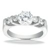 A diamond engagement ring features a large round central stone flanked by smaller round and oval diamonds in a silver setting.