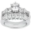 A silver ring features a central round diamond surrounded by smaller rectangular and round diamonds in a stepped design.
