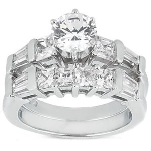 A silver ring features a central round diamond surrounded by smaller rectangular and round diamonds in a stepped design.