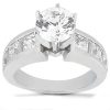 A silver ring features a large round diamond surrounded by smaller rectangular diamonds along the band.