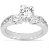 A silver engagement ring features a round center stone with rectangular and baguette-cut accents on the band.