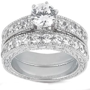 A silver wedding ring set featuring a central round diamond surrounded by smaller diamonds in a decorative band.