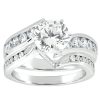 A white gold engagement ring features a large round diamond at the center, accompanied by smaller diamonds set along the shank.