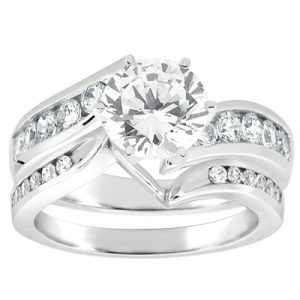 A white gold engagement ring features a large round diamond at the center, accompanied by smaller diamonds set along the shank.