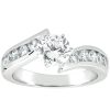 A silver engagement ring features a central round diamond with smaller diamonds set along the band.