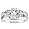 A silver engagement ring set features a central round diamond with additional smaller diamonds along the band.
